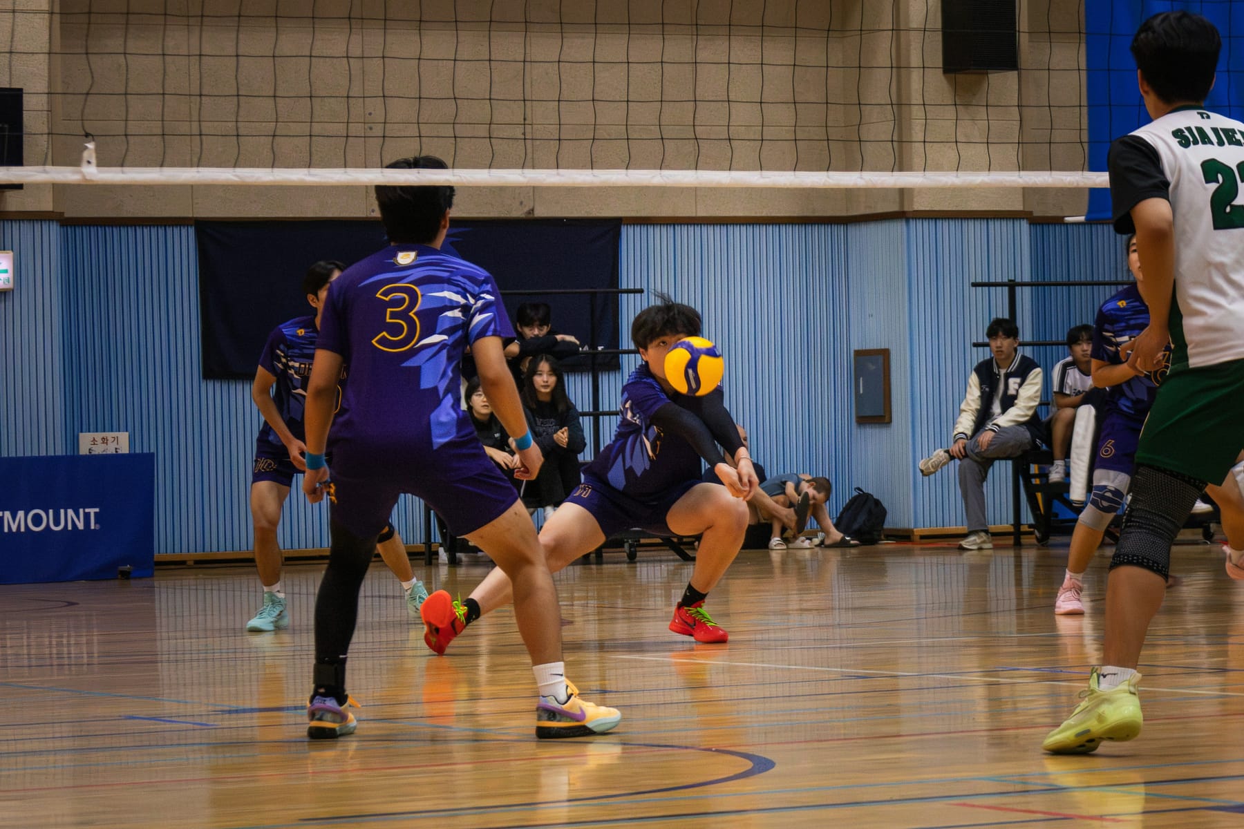 A defender low in the stance, passing a serve off the forearms