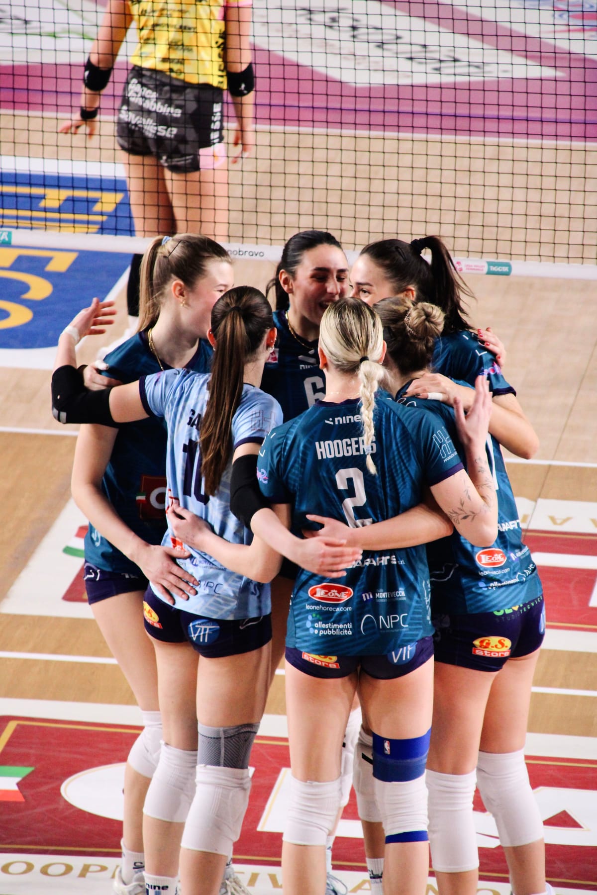 A team huddled together with arms around each other between points